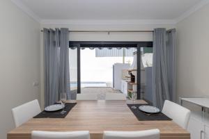 uma sala de jantar com uma mesa de madeira e cadeiras brancas em Villa Buganvilia by ALGARVEMANTA em Vila Nova de Cacela