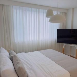 1 dormitorio con 1 cama blanca y TV en Stay Saeroc, en Geoje