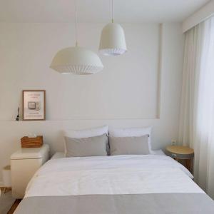 a bedroom with a white bed with two pendant lights at Stay Saeroc in Geoje 