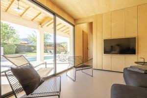 sala de estar con 2 sillas, TV y puertas correderas de cristal en Villa la Provenca -Architectural House, en Malaucène