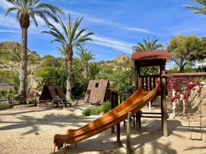 un parque infantil con tobogán en un parque con palmeras en Luxe Beach Three By Gloove, en Villajoyosa