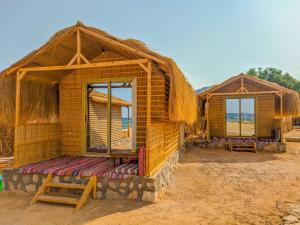 a couple of huts on the beach with the ocean at Baraka Camp in Taba