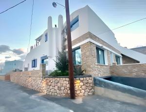 una casa blanca con una pared de piedra delante de ella en Rising Sun House Santorini en Firostefani