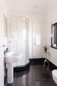 a white bathroom with a shower and a sink at Christie Mansion - Luxury Cottages in Shanklin
