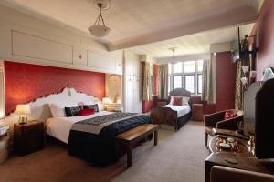 a hotel room with a large bed and a chair at Christie Mansion - Luxury Cottages in Shanklin