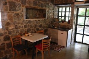 eine Küche mit einem Tisch und Stühlen in einer Steinmauer in der Unterkunft FARMAHOUSE in Orchomenós