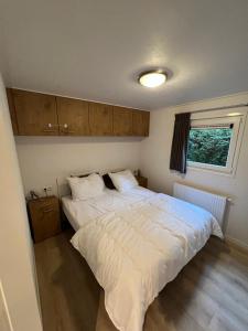 Un dormitorio con una gran cama blanca y una ventana en Chalet Hoenderloo en Hoenderloo