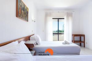 two beds in a hotel room with a window at #132 Velamar 414 by Home Holidays in Caliços +50 photos