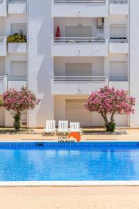a swimming pool with two chairs and a building at #132 Velamar 414 by Home Holidays in Caliços