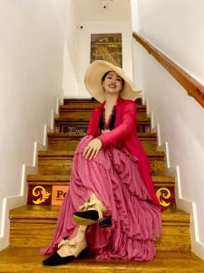 una mujer con un vestido rosa sentada en las escaleras en Red House By The River, en Oporto