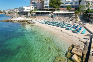 a beach with chairs and umbrellas and the water at Oceanic Overview Suites in Sarandë