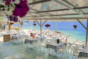 un restaurante en la playa con mesas y sillas en Oceanic Overview Suites, en Sarandë