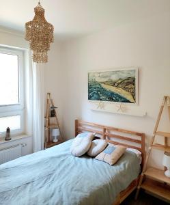 a bedroom with a bed with pillows and a chandelier at Apartament Morze Sztuki, Jantar in Jantar