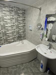 een badkamer met een bad en een wastafel bij Vatan Plaza in Tasjkent