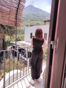 Eine Frau steht auf einem Balkon mit Bergblick. in der Unterkunft Ingrid Romantic House in Stromboli