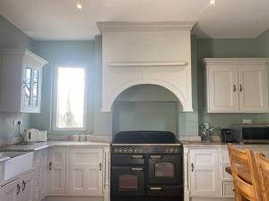 una cocina con armarios blancos y horno negro en Ballea Farmhouse en Cork