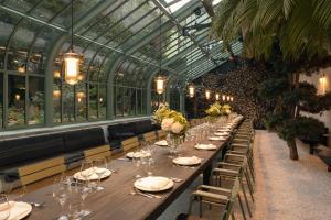 a long table in a greenhouse with glasses and flowers at Parkhotel Laurin in Bolzano