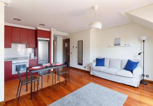 een woonkamer met een tafel en een witte bank bij Ático con terraza, vistas al mar y parking en playa de S Lorenzo in Gijón