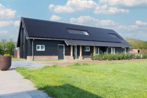 una casa negra con paneles solares. en Erve Mulder vakantiehuis met eigen jacuzzi en eigen sauna, en Weerselo