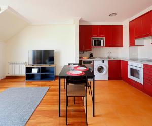 eine Küche mit roten Schränken sowie einem schwarzen Tisch und Stühlen in der Unterkunft Ático con terraza, vistas al mar y parking en playa de S Lorenzo in Gijón