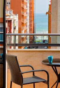 a table and a chair on a balcony with a view at Ático con terraza, vistas al mar y parking en playa de S Lorenzo in Gijón