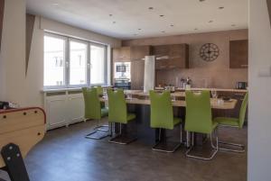 a kitchen with a large table and green chairs at Nouveau - Le Baby Player - Europa Park in Huttenheim