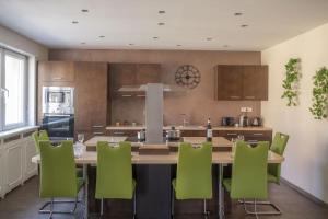 a kitchen with a large wooden table and green chairs at Nouveau - Le Baby Player - Europa Park in Huttenheim