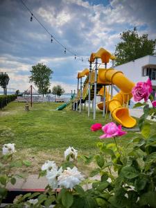 une aire de jeux avec un toboggan jaune et des fleurs roses dans l'établissement Voila Mamaia, à Mamaia
