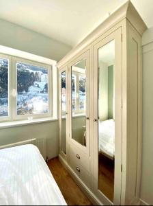 ein Schlafzimmer mit einem weißen Schrank und zwei Fenstern in der Unterkunft Brand-new, central apartment w/ VIEWS in Bad Gastein