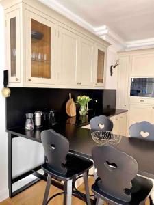 eine Küche mit weißen Schränken und schwarzen Thekenstühlen in der Unterkunft Brand-new, central apartment w/ VIEWS in Bad Gastein