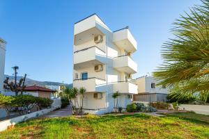 a tall white building with palm trees in front of it at Sunshine Garden Apts in Malia
