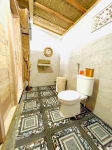 bagno con servizi igienici e pavimento a mosaico. di Batur cottage a Kubupenlokan