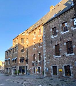 un grand bâtiment en briques avec le soleil brillant sur lui dans l'établissement Les Tanneurs, à Namur