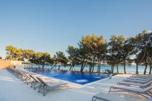a row of lounge chairs next to a swimming pool at Hotel Punta in Vodice