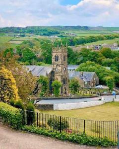 an old building with a clock tower in a field at Malkin Wood Studio - 15 min walk to Holmfirth centre in Holmbridge