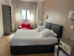 a bedroom with a large bed and a red chair at Hotel Amiraute in Cannes