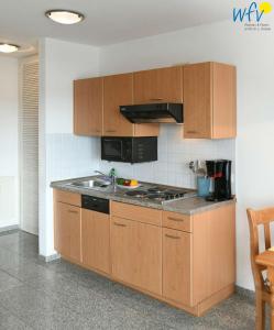 a kitchen with wooden cabinets and a stove top oven at Ferienappartements Am Neuensiener See Ferienwohnung 2 in Sellin