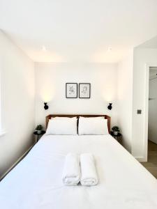 a white bedroom with a large white bed with two white towels at Luxury 1 Bed Flat - Shoreditch, Spitalfields & The City of London in London