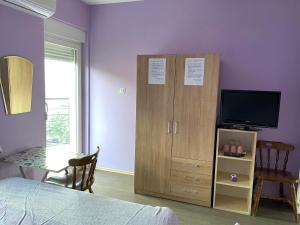 a bedroom with a bed and a tv and a cabinet at Guest House Trajkovic in Jagodina