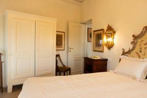 1 dormitorio con cama blanca y escritorio en Ai Leoni Ruggenti - Giardino Segreto con Vista sul Monferrato, en Ottiglio