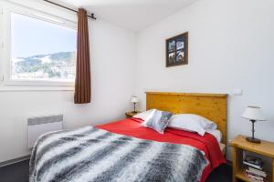 - une chambre avec un lit doté d'une couverture rouge et d'une fenêtre dans l'établissement Lagrange Vacances L'Orée des Cîmes, aux Angles