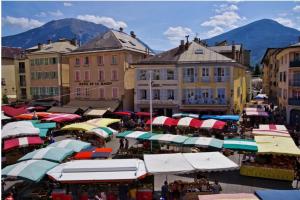 einen Markt mit vielen Sonnenschirmen in einer Stadt mit Gebäuden in der Unterkunft CHIC & MODERNE au coeur de la vie embrunaise in Embrun