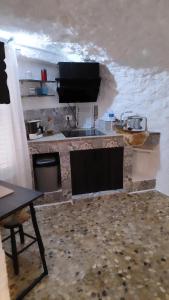 cocina con encimera de piedra, mesa y encimera en Cueva Rural El Sendero, en Pegalajar