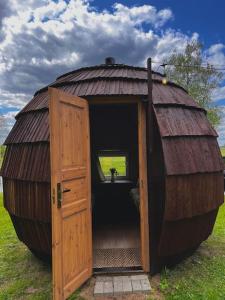 a large wooden hut with a door in a field at Mežagaiļu idiļļa in Rēzekne