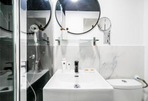 La salle de bains blanche est pourvue d'un lavabo et d'un miroir. dans l'établissement Apartments WS Louvre - Saint-Roch, à Paris