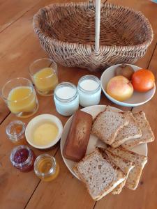 a table with a plate of toast and bread and glasses of orange juice at La cabane de l'oiseau in Couze-et-Saint-Front