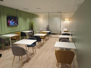 Habitación con mesas, sillas y TV en la pared. en HelloSky Air Rooms Madrid en Madrid