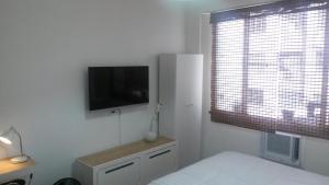 里約熱內盧的住宿－Loft Copacabana Avenida Atlantica，一间白色卧室,墙上配有电视