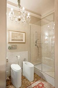 baño con aseo y ducha y lámpara de araña. en Castellata La Suite, en Bolonia