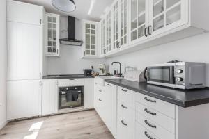 een witte keuken met witte kasten en een magnetron bij Golden Apartments Gdansk&K2A in Gdańsk